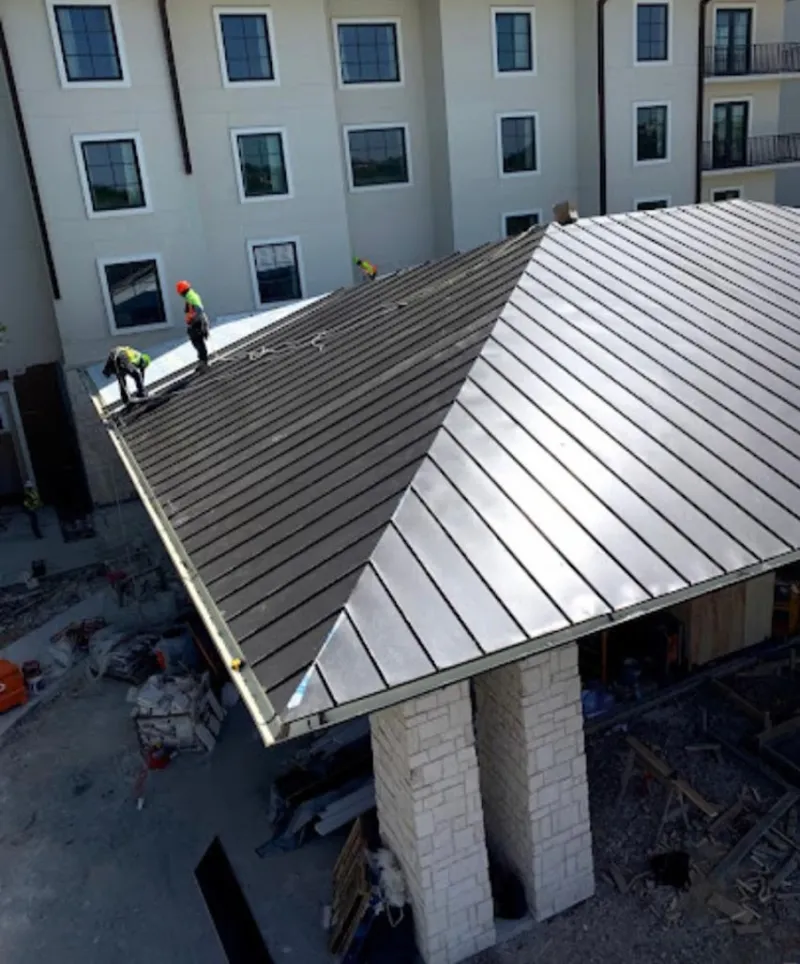 Crew installing standing seam metal roof panels on a commercial project in Cazenovia